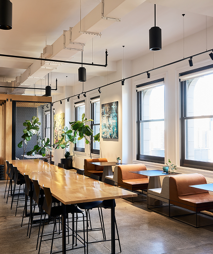 Office cafe with a long communal table, banquette seating and arched windows