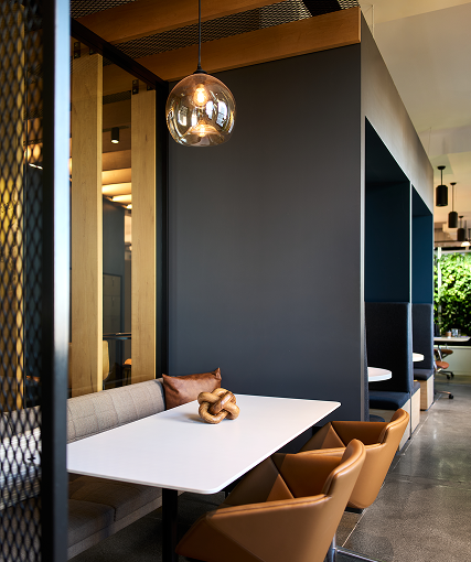 Booth seating beneath a globe pendant light, with tan leather chairs and a living green wall