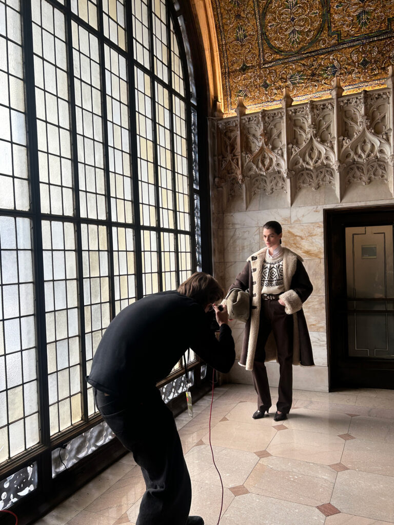 Man photographs a visitor beside the Woolworth Building's tall Gothic windows