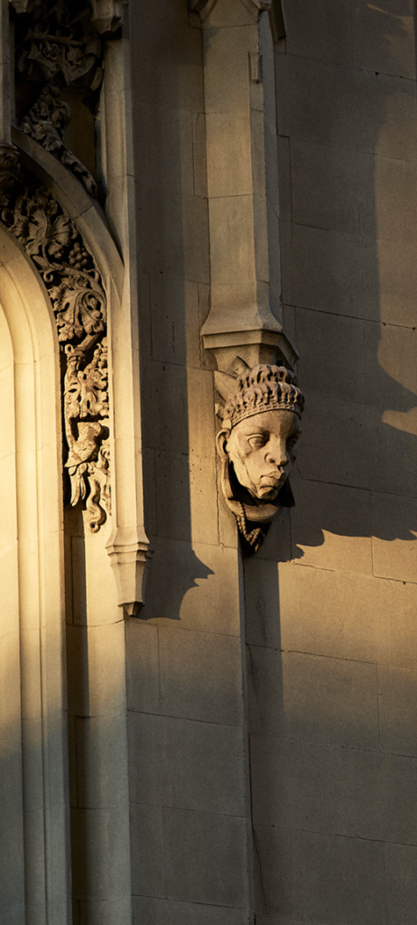 Carved stone face on a sunlit column at the Woolworth Building