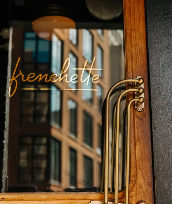 Frenchette's gold script lettering on the restaurant's glass door