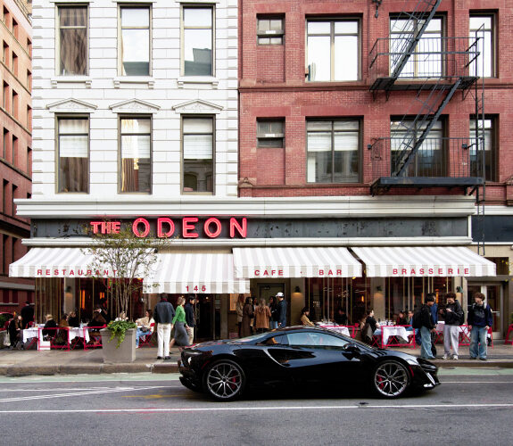The Odeon's red neon sign and striped awnings above its sidewalk tables