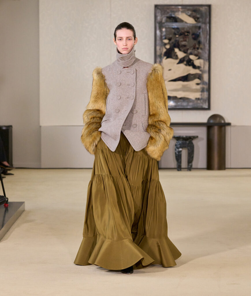 Model in a pleated gold skirt walks the Altuzarra runway