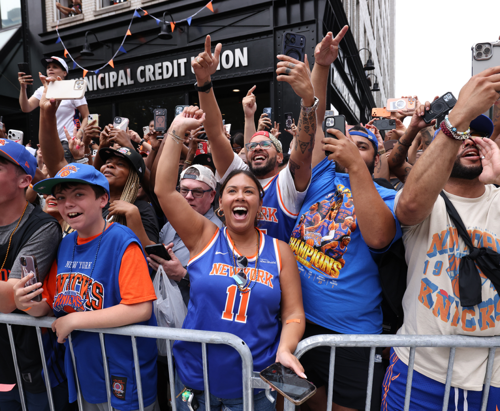 Knicks fans cheer behind a parade barricade