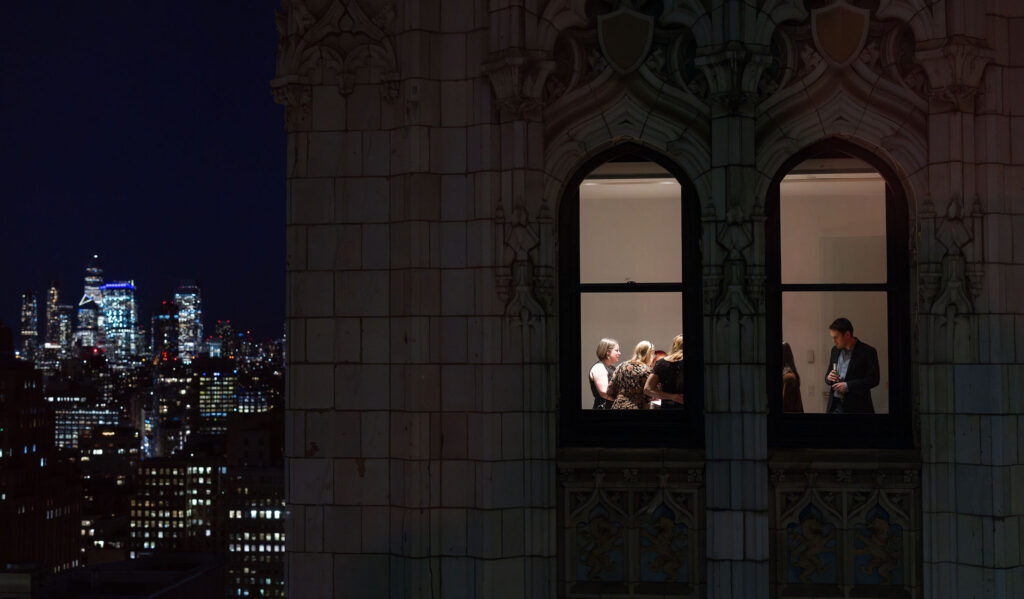 Guests visible through a Gothic window at night