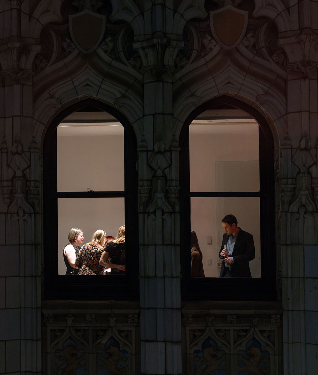 Open House New York guests seen through the Woolworth Building's pointed arch windows after dark