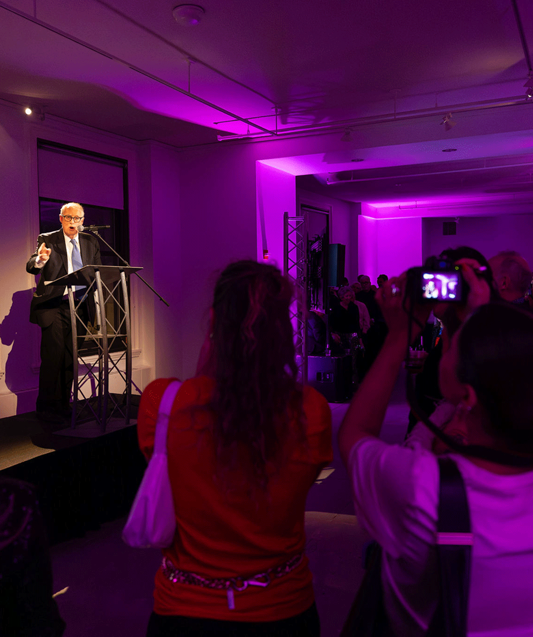 Speaker addresses guests in a purple-lit event space