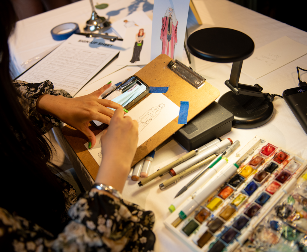 Artist paints a fashion illustration at Pickle's anniversary event