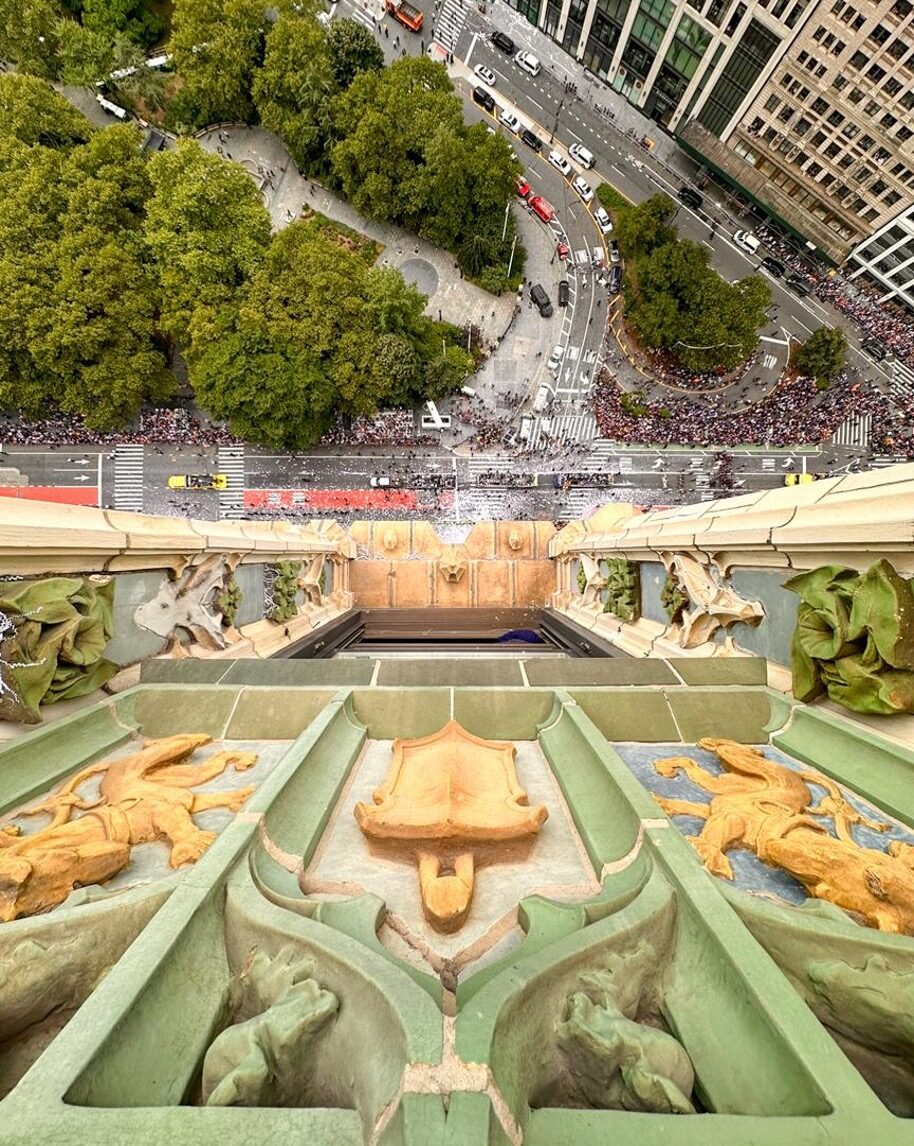 View down the Woolworth Building's terracotta parapet and griffins to the crowds on Broadway far below