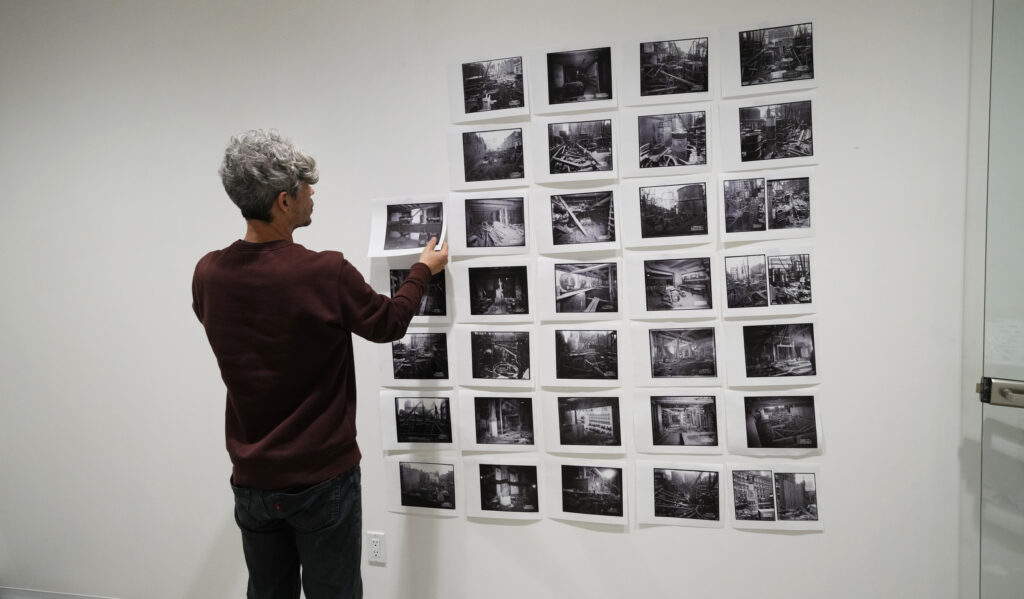 Visitor arranges black-and-white photographs in an exhibition