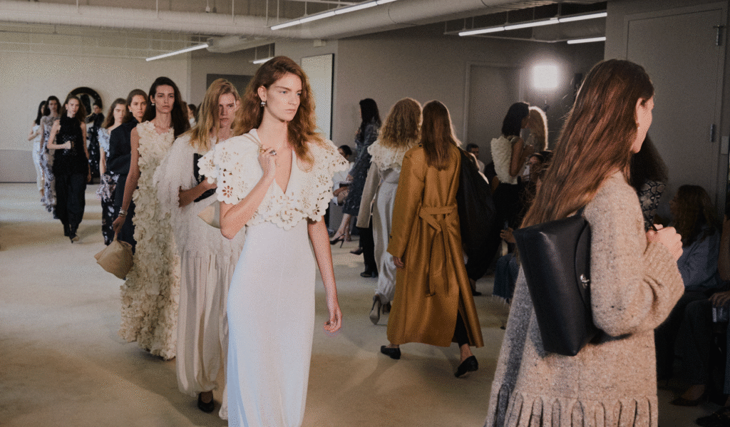 Models in cream and white looks walking together at the close of the Altuzarra show