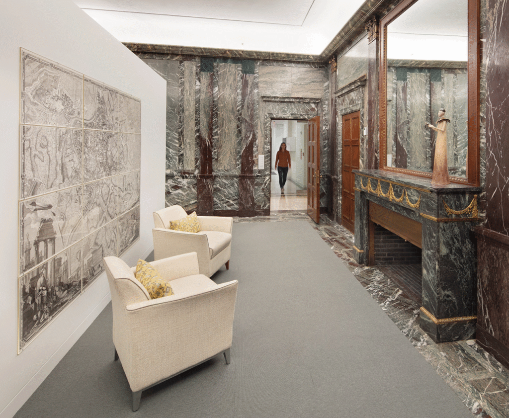 Marble-clad lounge with armchairs, a period fireplace and a large framed drawing