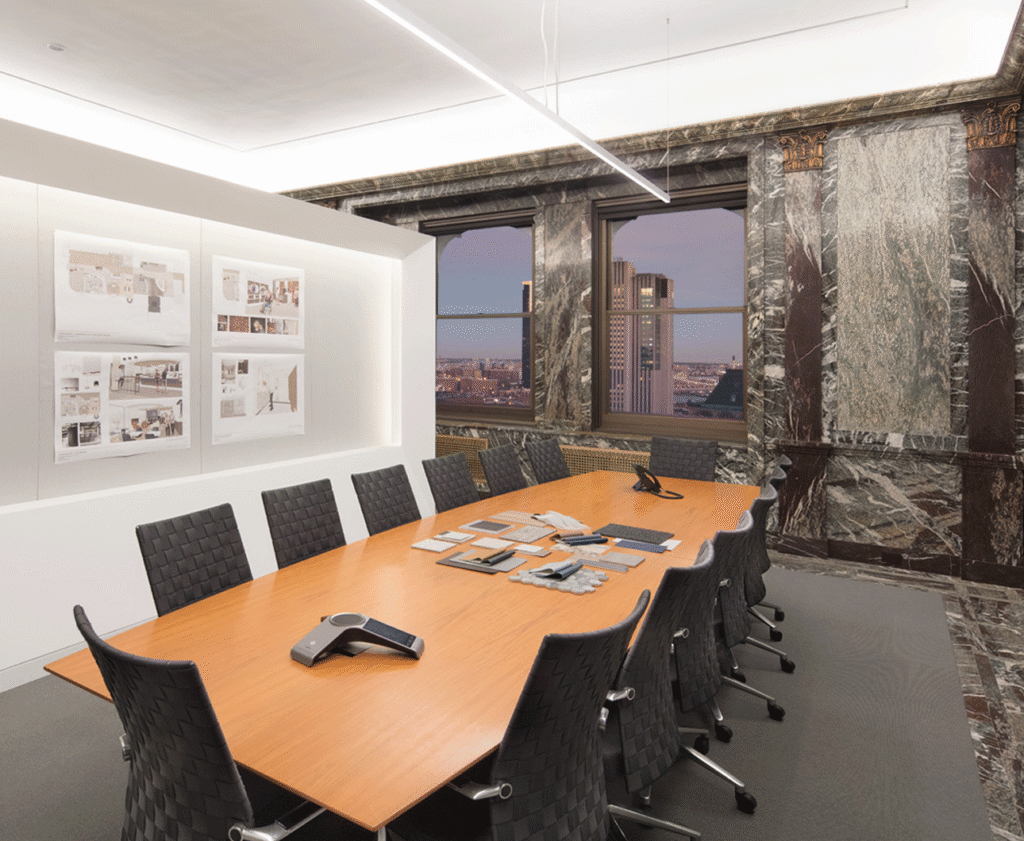 Conference room with a wood table and marble walls, overlooking the city at dusk